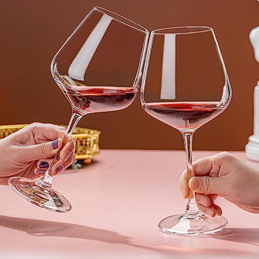 Crystal red wine glass filled with red wine, wide bowl design.
