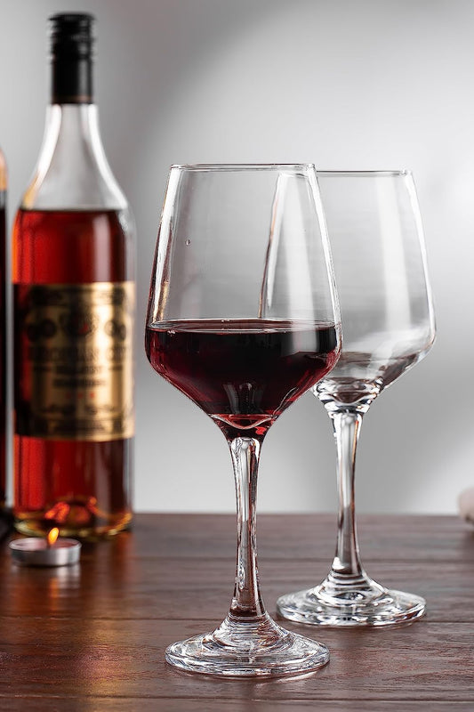 Wine glass filled with red wine, placed on a table.