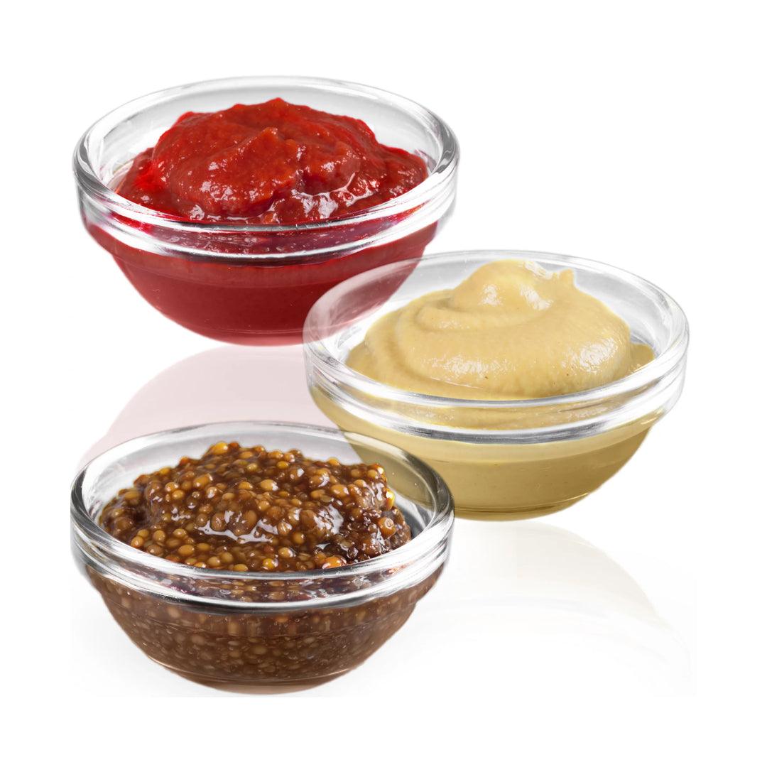 Stackable glass bowls on a table with dips and sauces.
